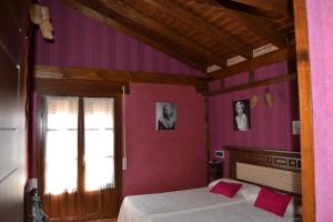 a bedroom with a bed with pink walls and a window at El Lagar in Canalejas de Peñafiel