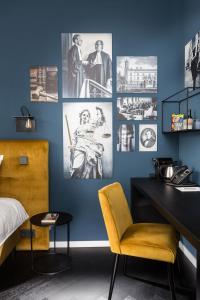 a bedroom with a blue wall with pictures and a yellow chair at Court Hotel Utrecht City Centre in Utrecht