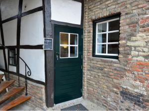 une porte verte sur le côté d'un bâtiment en briques dans l'établissement Vakantiewoningen 'Hoeve de Witte Olifant', à Noorbeek