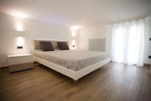 a bedroom with a white bed and a wooden floor at Residence Torino in Chioggia