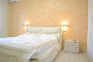 ein Schlafzimmer mit einem weißen Bett mit zwei Lichtern an der Wand in der Unterkunft Casa Aurora B&B in Chieti