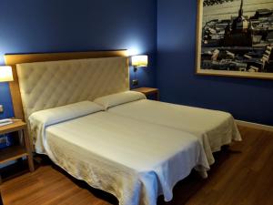 um quarto com uma grande cama branca com paredes azuis em Hospedería Santa Elena em San Carlos del Valle