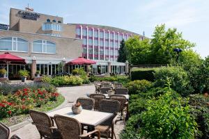 une rangée de tables et de chaises devant un bâtiment dans l'établissement Carlton Oasis Hotel, à Spijkenisse