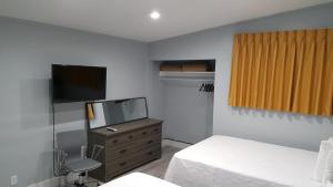 a bedroom with two beds and a tv and a dresser at The Palms On Ocean in Pompano Beach