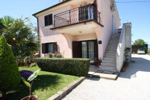 ein rosafarbenes Haus mit einer Treppe und einem Balkon in der Unterkunft Apartments Katica in Gedići