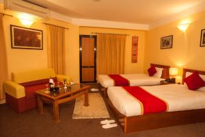 una camera d'albergo con due letti e un divano di Royal Astoria Hotel a Kathmandu