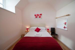 a bedroom with a large bed with a red blanket at Lady Macbeths Rest in Banchory