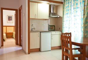 a kitchen with a white refrigerator and a table at Apartamentos Royal in Lloret de Mar