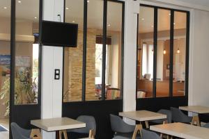 un ristorante con tavoli e sedie e una TV a parete di Hotel Bellevue a Brest