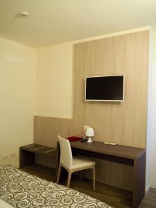 サン・ペッレグリーノ・テルメにあるHotel Riposoのデスク、壁掛けテレビが備わるホテルルームです。