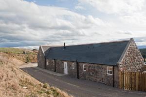 a stone building with a black roof on a road at Lady Macbeths Rest in Banchory