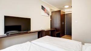 a bedroom with a bed and a flat screen tv at 24Seven Hotel Nürnberg in Nürnberg