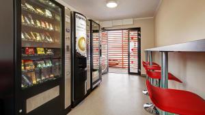 a restaurant with a bar with red chairs and a refrigerator at 24Seven Hotel Nürnberg in Nuremberg