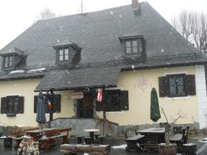 a building with tables and umbrellas in the snow at Landgasthof Negrean in Modriach