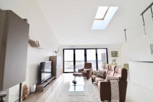 a living room with couches and a flat screen tv at Appartement T4 Vue Unique in Rodez