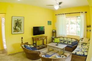 uma sala de estar com um sofá e cadeiras e uma televisão em Casa em condominio de alto padrao em Ilhabela