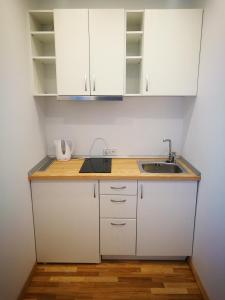 uma cozinha com armários brancos e um lavatório em Klevas em Karklė