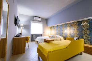 a hotel room with two beds and a yellow couch at Un B&B al Belvedere in Enna