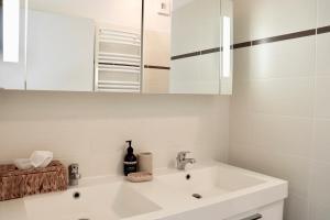 baño blanco con lavabo y armario en Appartement T4 Vue Unique, en Rodez