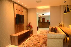 een woonkamer met een bank en een flatscreen-tv bij Hotel Flamboyant in Catalão