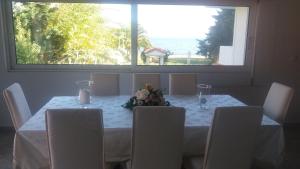 a dining room table with white chairs and a large window at Beach House Villa in Nea Makri