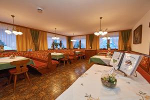 un restaurante con sofás, mesas y ventanas en Pension Bartlbauer, en Ramsau am Dachstein