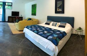 a bedroom with a large bed and a yellow chair at Suite 9, Manuel Antonio in Quepos