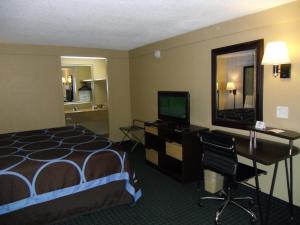 Habitación de hotel con cama, escritorio y TV. en Super 8 by Wyndham Lantana West Palm Beach en Lantana