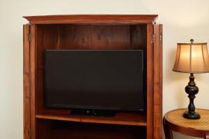a television in a wooden entertainment center with a lamp at Pacific Marina Inn in Honolulu