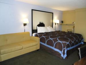 a hotel room with a bed and a couch at Super 8 by Wyndham Lantana West Palm Beach in Lantana