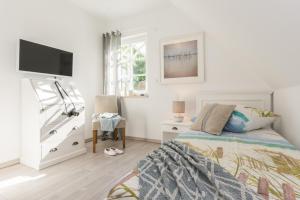 a white bedroom with a bed and a tv at Ferienhaus Ostseehaus Seegras mit Kamin in Prerow