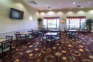 a dining room with tables and chairs and a flat screen tv at Ashmore Inn and Suites Amarillo in Amarillo