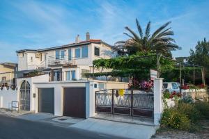 a white house with a gate and a palm tree at Apartman Antea in Trogir