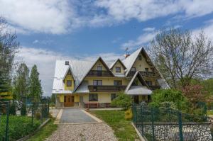 una grande casa gialla con tetto di metallo di Dom Wypocz Pod Litwinką Apartamenty a Białka