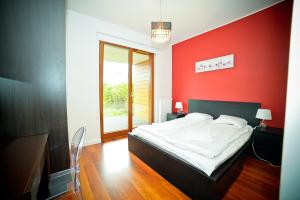 グディニャにあるLily Apartment Orłowo - Hav Apartsの赤い壁のベッドルーム1室、ベッド1台が備わります。