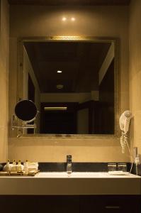 a bathroom with a large mirror above a sink at The Cabbana Resort & Spa in Phagwāra