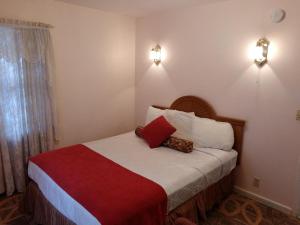 1 dormitorio con 1 cama con manta roja y blanca en Nevada City Inn, en Nevada City