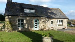 an old stone house with a grass yard at Ferienhaus Cottage Maison typique in Brignogan-Plage