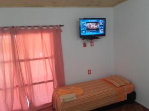 1 dormitorio con 1 cama y TV en la pared en Hotel Brisas de Garupa en Garupá