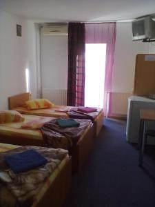 a room with three beds and a window at Pensiunea Raffael in Otopeni