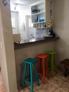 a kitchen with three colorful stools at a counter at Casa Riviera de São Lourenço in Riviera de São Lourenço