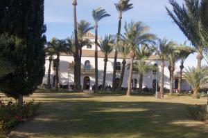 a building with palm trees in front of it at Hacienda Requelme Golf Resort Apartment in Sucina