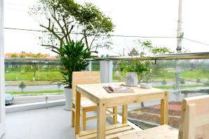 una mesa de madera y sillas en un balcón con ventana en Co Bon Beachside en Hoi An
