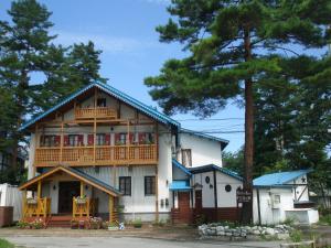 a large white house with a porch and a balcony at Alpine Wind in Hakuba