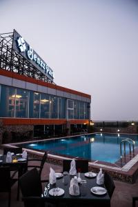 a large swimming pool with tables and chairs in front of a building at Hotel Benzz Park Vellore in Vellore