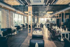 a dining room with tables and chairs and windows at Hotel Benzz Park Vellore in Vellore