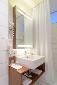 a bathroom with a white sink and a mirror at Kyriad Vienna Altmannsdorf in Vienna