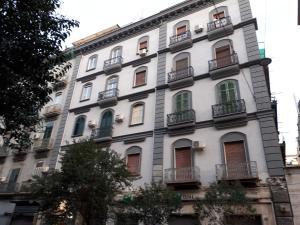 Un edificio alto y blanco con ventanas y balcones. en Le Villanelle B&B, en Nápoles