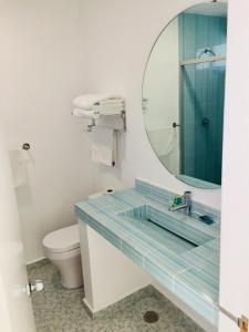 een badkamer met een wastafel met een spiegel en een toilet bij Hotel Palmas Cocoyoc in Cocoyoc