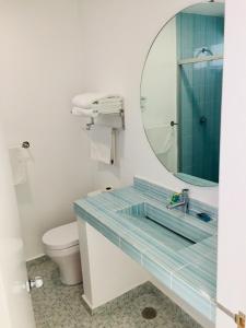 a bathroom with a sink with a mirror and a toilet at Hotel Palmas Cocoyoc in Cocoyoc